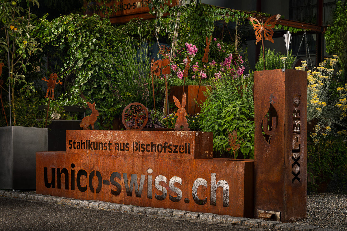 Bepflanztes Hochbeet mit natürlicher Rostpatina, Schriftzug «unico-swiss.ch» und Stahlfiguren